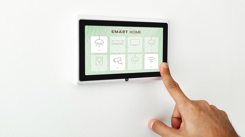 How to Create a DIY Smart Home on a Budget - a finger pressing on smart home automation panel monitor attached to a wall